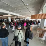 Interior de la UTU con personas recorriéndola, techos colgantes con luminaria y recepción en forma de círculo en madera